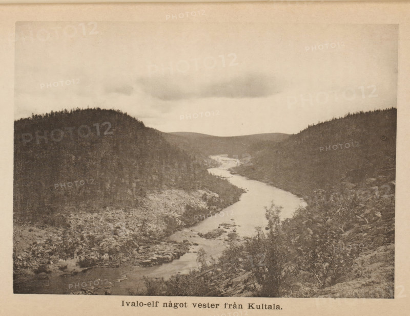 Ivalo-elf något vester från Kultala, View of the river Ivalo in Kultala, page, photomechanical print, photographer: Karl Granit, Sápmi, cliché maker: Phototypische Institut, Berlin, c. 1875 - in or before 1885, paper, collotype, photoprint, height 116 mm x width 161 mm, river, dale, valley, Ivalo, A sepia-toned landscape photograph showing a winding river flowing between forested hills, with tree-covered slopes on both sides and rocky banks visible along the water; the sky above is mostly light with a few darker cloud formations, and the foreground includes shrubs and scattered rocks.