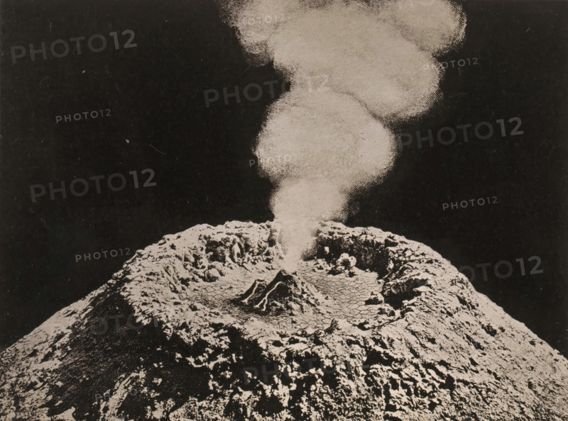 Crater of Vesuvius, page, photomechanical print, number: 'Tafel II.', photographer: James Nasmyth, clichémaker: Strumper & Co, Hamburg (city), 1864, paper, collotype, photoprint, height 152 mm x width 196 mm, volcano, Mount Vesuvius, A black-and-white image showing a rough textured mound with uneven, cracked surfaces and ridges occupying the lower portion, and a plume of lighter-toned, grainy smoke rising from its center against a dark background.