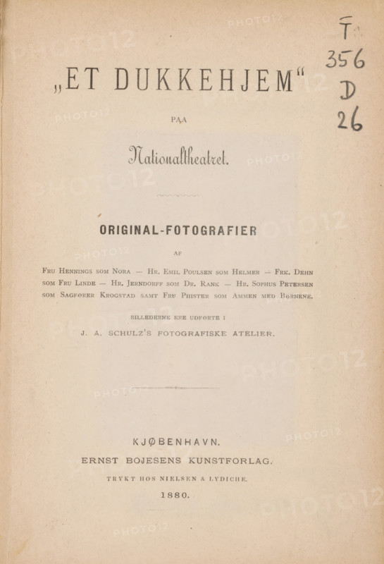 Et dukkehjem' paa Nationaltheatret, book, publisher: Ernst Bojesens Kunstforlag, Copenhagen (city), 1880, Ernst Bojesens Kunstforlag, publisher, textile materials, pasteboard, paper, linen (material), printing, albumen print, height 190 mm x width 129 mm x thickness 6 mm, A faded page with a warm beige paper texture and darker edges, showing a large centered heading area and several lines of printed lines in varied typefaces and sizes; the top right margin has several handwritten marks in dark ink running vertically; faint horizontal blemishes and small spots appear across the page, along with a thin decorative line near the middle; the paper shows subtle vertical crease and edge wear on the left side and overall slight discoloration from age.