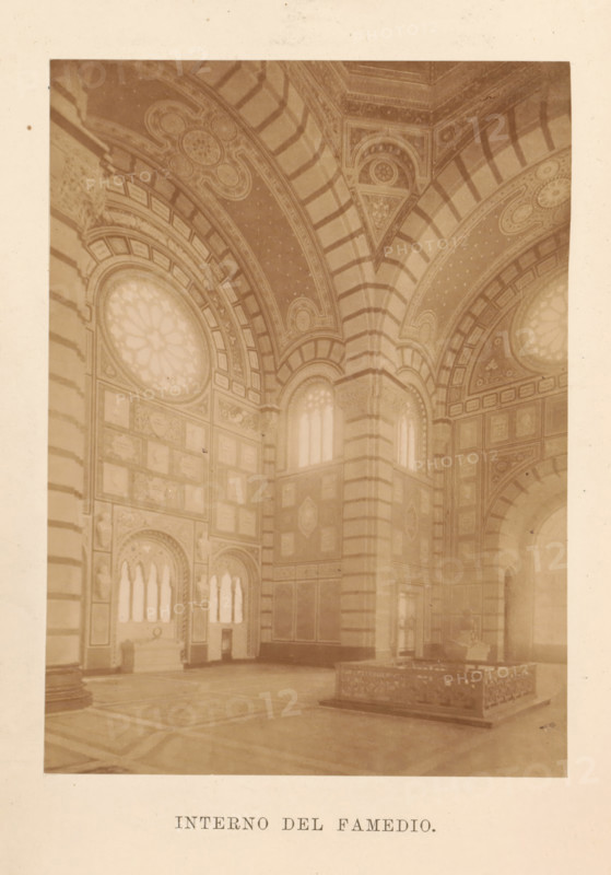 Guida del Famedio nel cimitero monumentale di Milano, book, number: '1 B 65', 1888, pasteboard, paper, printing, albumen print, height 261 mm x width 178 mm x thickness 20 mm, A sepia-toned photograph of an ornate interior space showing tall arched ceilings with striped ribbing and decorative patterns, large circular stained-glass windows set into arched frames, elaborately paneled walls with rectangular and square panels filled with decorative motifs, tall narrow arched windows with tracery, a massive central pier with horizontal banding, a raised rectangular stone or marble enclosure with carved sides on the floor, and a patterned floor beneath the architectural elements.