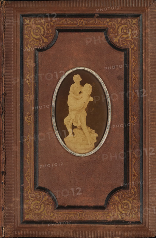 Poetry album of Everdine Goedbloed, scrapbook, verse album, Poetry album of Everdine Goedbloed with a photo of a sculpture on the front cover., compiler (person in literature): anonymous, Netherlands, 1860 - in or before 1879, compiler (person in literature), photographer, textile materials, biological material, inorganic material, paper, linen (material), metal, plant material, albumen print, autotype, embroidering, color on edge, photo album with a brown linen cover with blind embossing in gold and black and on the front cover an oval albumen print with a metal frame, the album contains paper sheets with gold on the edge, height 227 mm x width 151 mm x thickness 13 mm x width 294 mm, height 82 mm x width 51 mm, sculpture, A rectangular cover with a textured brown surface and a raised decorative border featuring ornate floral scrollwork in muted gold, with darker inset panels and ribbed edges, centered by an oval framed window containing a monochrome silhouette of a standing figure ca...