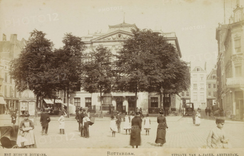 The Boymans Museum. Rotterdam., View of the Boymans Museum in the Schielandshuis in Rotterdam, photograph, cabinet photograph, Part of a Leporello album with photos of Rotterdam., photographer: attributed to Andries Jager, Rotterdam, c. 1867 - c. 1900, Attributed to, paper, pasteboard, albumen print, height 94 mm x width 157 mm, Person, railway, train, bridge in village across river, canal, viaduct, Schielandshuis, A wide street scene with a large classical building partly obscured by tall leafy trees in front, flanked by multi-story buildings on either side, a paved open area in the foreground with groups of people including women in long dresses and hats, children in light-colored clothing, and men in dark coats, some walking and some standing, a decorative kiosk or small pavilion to the left, a lamppost near the center, a carriage or cart parked near the right side, and architectural details such as columns and ornate facades visible on the buildings.