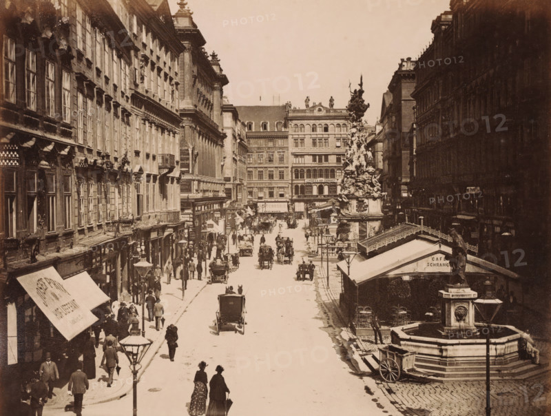 Wien. Der Graben., View of Der Graben in Vienna with shops, carts, pump and the Vienna Plague Column, photograph, Part of Travel Album with photos of sights in Germany and Austria and of works of art., photographer: A. Wimmer, Vienna, c. 1880 - c. 1895, Lower Austria, paper, albumen print, height 205 mm x width 266 mm, shop, store, monument, statue, utilitarian, public pump or water fountain, street (city(-scape) with figures, staffage), animal traction, animal-drawn vehicle (carriage etc.), piece of sculpture, reproduction of a piece of sculpture (sculpture), A wide sepia street scene with tall multi-story buildings flanking a broad roadway, a decorative column topped with sculptural figures rising near the right side, a stone fountain with a statue and basin in the foreground right, horse-drawn carriages and people walking along the street and sidewalks, awnings and streetlamps along building fronts, a row of windows and ornate architectural details on the left buildings, a canopy-co...
