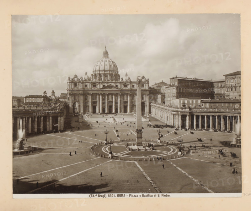 View of St. Peter's Square in Vatican City, with the Vatican Obelisk in the foreground, Roma - Piazza e Basilica di S. Pietro, photograph, Part of Photo album with photographs of landmarks and artworks in Italy., number: '8301', photographer: Edizioni Brogi, Vatican City, c. 1875 - in or before 1907, Edizioni Brogi, photographer, paper, gelatin silver print, height 200 mm x width 250 mm, square, circus, church (exterior), obelisk, needle, St. Peter's Square, Vatican Obelisk, A wide plaza with radiating paving lines and a circular central area containing a tall obelisk surrounded by low bollards and ornate lampposts, flanked by two long colonnaded buildings with rows of columns and balustrades topped by statues, an ornate fountain spouting water on the left, and a large classical basilica with a central dome, sculpted pediments, columns at its façade, and smaller domes and decorative statues along its roofline; scattered small groups of people and a few carriages are visible on the plaz...