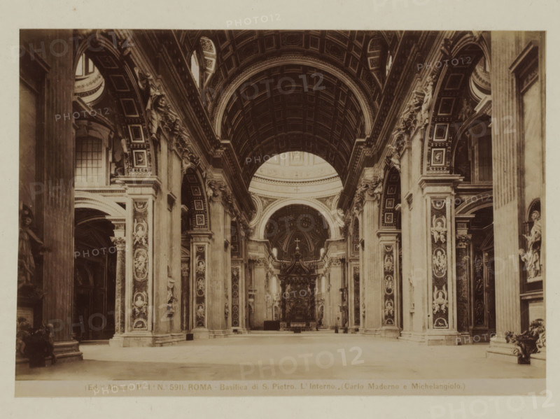 Basilica di S. Pietro. L'Interno (Carlo Maderna e Michelangiolo), Interior of St. Peter's Basilica in Rome, Italy, Roma, photograph, number: 'Po. Io. No. 5911.', photographer: Fratelli Alinari, Vatican City, 1852 - 1900, pasteboard, paper, albumen print, height 100 mm x width 142 mm, height 168 mm x width 212 mm, interior of church, St. Peter's Basilica, A wide interior view of a grand ornate nave with a high coffered barrel vault and a large arched dome visible toward the rear, flanked by tall paired columns and pilasters decorated with relief panels and sculpted figures; elaborate archways and richly detailed cornices run along both sides, with niches holding statues and decorative moldings; the floor is open and spacious leading toward a raised altar area under a decorated arch, and the overall palette is sepia-toned with strong contrasts between shadowed recesses and illuminated architectural surfaces.