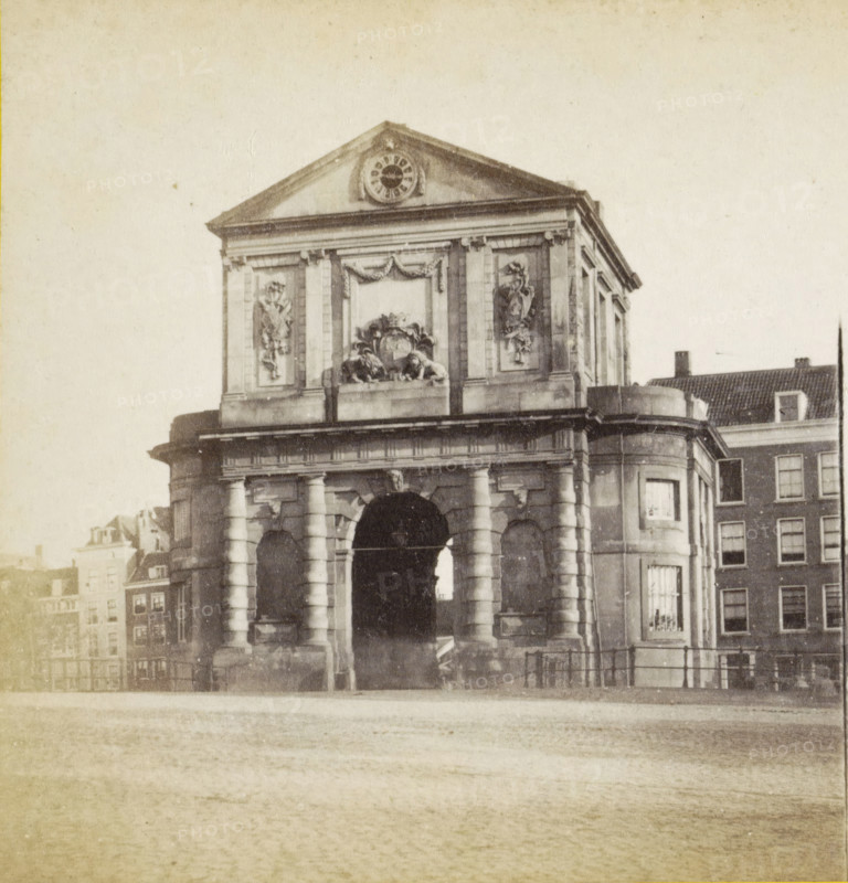 Delftschepoort Rotterdam, View of the Delftsche Poort in Rotterdam, stereograph, Rotterdam, 1873 - 1890, photographer, pasteboard, paper, albumen print, height 85 mm x width 170 mm, city-gate, Delftsche Poort, A stone archway structure with columns and ornate carvings, including decorative relief panels and sculpted figures, topped by a triangular pediment with a circular ornamental feature, flanked by adjacent buildings with windows and tiled roofs, a paved foreground leading to the arch, and a horizontal railing near the base of the building.