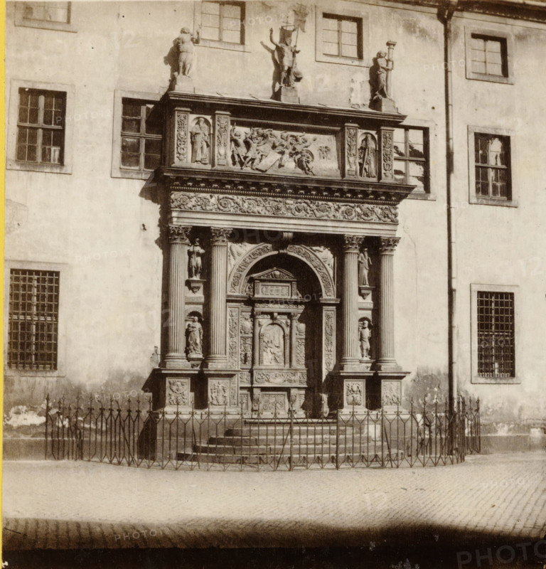 Portail de Sainte-Sophie, à Dresde., Portal der Sophienkirche, in Dresden, Portal of the Sophienkirche in Dresden, Saxe., Sachsen, stereograph, number: 'No. 430.', number: '430', photographer: Athanase Clouzard (possibly), Dresden, 1860 - 1879, Saxony, pasteboard, paper, albumen print, albumendruk, height 88 mm x width 175 mm, parts of church exterior and annexes: portal, Sophienkirche (Dresden), A sepia-toned photograph of a building facade showing a richly carved stone doorway with an ornate arch and decorative panels flanked by fluted columns and sculpted figures on pedestals, a horizontal frieze with reliefs above the doorway, and additional statues on the roofline. The wall around the entrance features rectangular windows with divided panes at various heights, some with bars, and a vertical downpipe running beside one window. In front of the entrance a low set of steps leads up to the doorway and a metal fence with pointed finials encloses the area. The ground in front of the fenc...