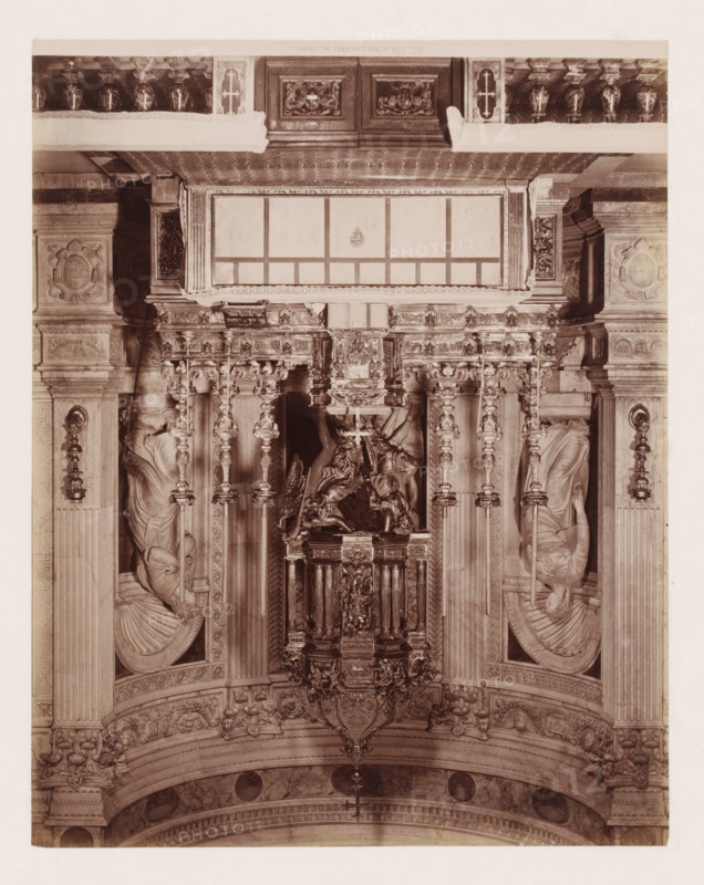 Altare d'Argento (del duomo), Altar in the cathedral in Pisa, Italy, Pisa, photograph, number: '3452.', 1851 - 1900, photographer, Tuscany, pasteboard, paper, albumen print, albumendruk, height 384 mm x width 307 mm, altar, Cathedral (Pisa), An ornate interior view showing a richly carved altar area with vertical columns and decorative pilasters, an elaborate central sculptural canopy with detailed relief work, and a suspended ornamental lantern or canopy piece; sculpted figures are set into niches on either side, each draped in flowing robes and positioned within rounded shell-like alcoves; the upper section features a framed rectangular panel with decorative molding and a patterned cornice, while the surrounding stonework includes carved medallions, floral motifs, and acanthus detailing; balustrades and carved panels run along the top edge and the lower arch displays patterned friezes and round medallion insets.