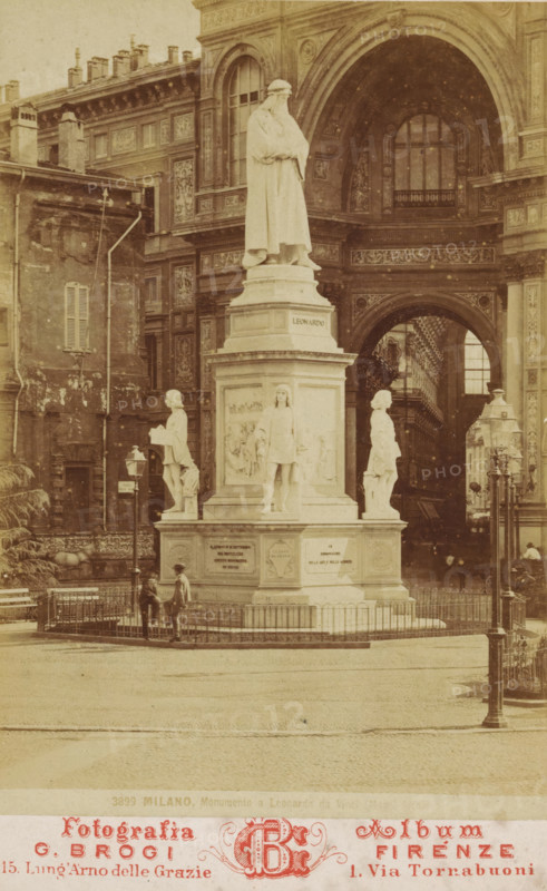 View of the monument to Leonardo da Vinci in Milan, Milano, Monumento a Leonardo da Vinci ..., cabinet photograph, number: '3899', inscription: 'Estese Collezioni, di Vendute d'Italia, d'Égitto e di Palestina, edile in diversi formati., Fotografie di Disegnie Pitture riprodotte dagli originali, grandissimi panorama di un sol pezzo, Grandiosa collezione delle principali, Pitture sistenti nelle Gallerie d'Europa tratta, dalle migliori Stampe', name: 'AC de Roo', address: 'Fotografia Album, G. Brogi Firenze, 15. Lung'Arno delle Grazie 1. Via Tornabuoni', annotation: 'Souvenir de ...', photographer: Giacomo Brogi, Milan, 1864 - 1881, Lombardy, paper, pasteboard, albumen print, height 164 mm x width 106 mm, Person, Leonardo da Vinci, monument, statue, A sepia-toned photograph of a large marble statue on a tall plinth situated in a paved square, the statue depicting a robed standing figure with folded arms atop the pedestal and four smaller sculpted figures positioned around the base; the mo...