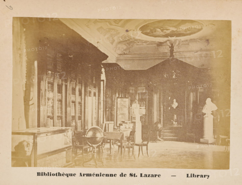 Monastery Library of San Lazzaro degli Armeni, Venice, Bibliothèque Arménienne de St. Lazare, Library, photograph, page, number: '6', c. 1874 - in or before 1879, photographer, paper, albumen print, height 89 mm x width 130 mm, Photo on unnumbered page opposite page 6., abbey, monastery, convent, Roman Catholic church, public library, San Lazzaro degli Armeni, A sepia-toned interior photograph showing a room with tall bookcases along the left wall and ornate ceiling decoration, a large canopy or dark drapery hanging toward the back, tables and chairs scattered across the floor, a globe mounted on a stand near a table, display cases and pedestals with busts and objects, and patterned flooring with soft light entering from the left.