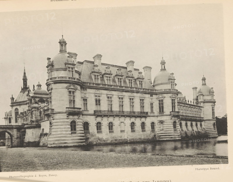 Chateau de Chantilly (Coté du Champ de Courses), View of Château de Chantilly, page, photomechanical print, inscription: '(Château Moderne) (Château Ancien)', photographer: H. Rouxel, Chantilly, cliché maker: Jules Royer, Nancy, c. 1886 - in or before 1891, printer (person), paper, collotype, photoprint, height 120 mm x width 174 mm, Print on unnumbered page., castle, Château de Chantilly, A large stone building with ornate architectural details sits beside a body of water, featuring rounded corner towers topped with domes and small lantern structures, a row of rectangular windows with decorative frames along an upper level, and arched openings at the lower level; a balustraded balcony runs across part of the facade, chimneys and dormer windows project from the steep roofline, and a distant spire and additional domed structures are visible behind the main block, all rendered in a monochrome, slightly aged photographic tone.