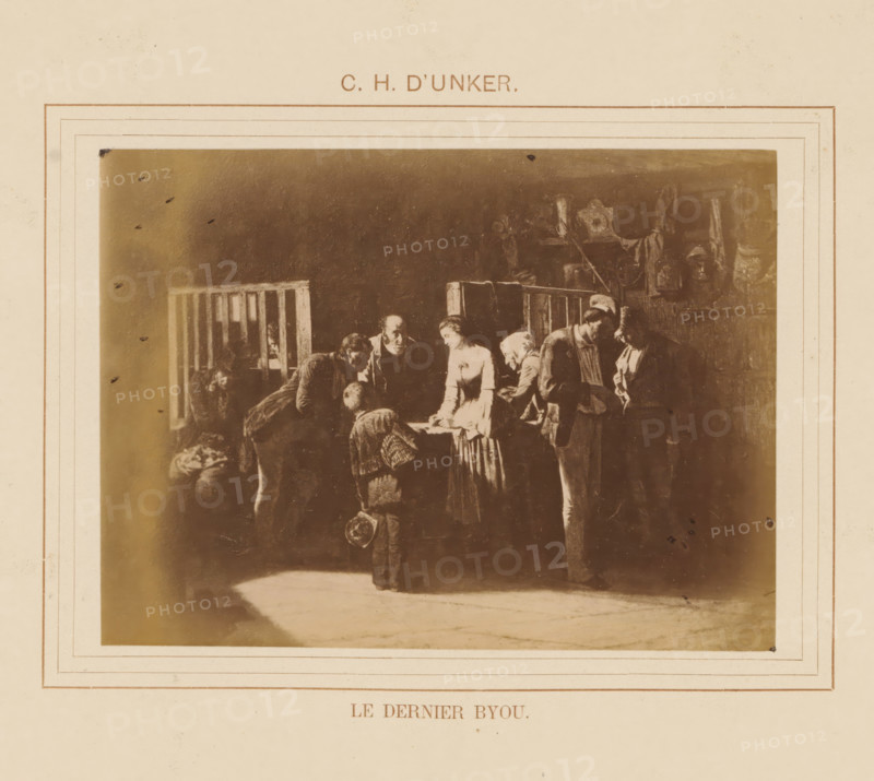 Le dernier byou, Photo reproduction of Le dernier byou by Carl Henrik D'Unker, photograph, reproduction, page, after painting by Carl Henrik D'Unker, c. 1878 - in or before 1883, Carl Henrik D'Unker, photographer, after painting by, paper, albumen print, albumendruk, height 96 mm x width 131 mm, painting, drawing and the graphic arts, A faded sepia image mounted on a cream paper with decorative rectangular borders shows a dim interior scene of several people gathered around a table; a woman in a light dress stands at the center leaning slightly forward, surrounded by men and children in darker clothing who are bending or standing close by, one child holding a hat and facing the table; in the background there are wooden railings and indistinct wall hangings and objects, with shadows and worn textures throughout the image.