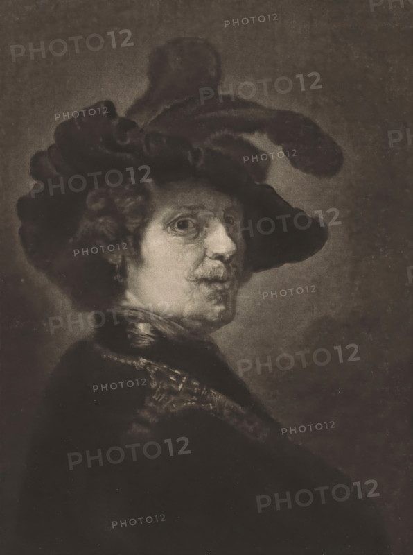 Portrait of a man with a feathered beret, print, A soldier dressed in a cloak and a beret with feathers., printmaker: Frans Everbag (signed by artist), after painting by Rembrandt van Rijn, 1903 - 1913, paper, mezzotint, proof print, height 288 mm x width 207 mm, head-gear: beret, A sepia-toned portrait of a person turned in three-quarter profile wearing a large dark hat with a wide brim and a tall feathered plume, with curly hair visible beneath the hat and a mustache and subtle facial lines, dressed in a dark garment with a patterned collar or sash, set against a plain darker background and framed by a lighter border.