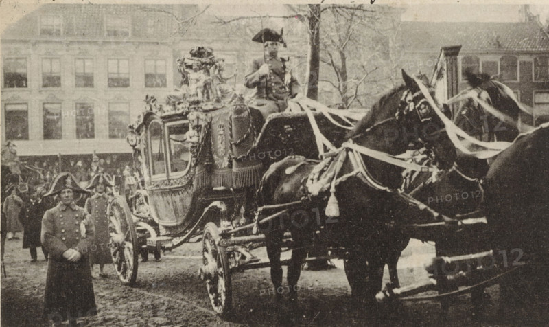 The golden coach of the wedding procession of Wilhelmina, Queen of the Netherlands, and Hendrik of Mecklenburg-Schwerin in The Hague on February 7, 1901, postcard, photomechanical print, The golden coach of the wedding procession of Wilhelmina and Hendrik in The Hague on February 7, 1901. In the right margin a line of Dutch text., inscription, clichémaker: anonymous, Netherlands, photographer, paper, collotype, photogravure, height 90 mm x width 142 mm, The title mentioned here refers to the highest title obtained by the person portrayed, not necessarily to the title the person portrayed bears in this image., Person, Hendrik (Prince of the Netherlands (1876-1934)), Wilhelmina of the Netherlands, (civil) marriage ceremonies, animal traction, animal-drawn vehicle (carriage etc.), Marriage of Queen Wilhelmina and Prince Hendrik, The Hague, Period, 1901-02-07, A sepia-toned street scene showing an ornate, horse-drawn carriage with decorative trim and carved details, draped fabric on its si...