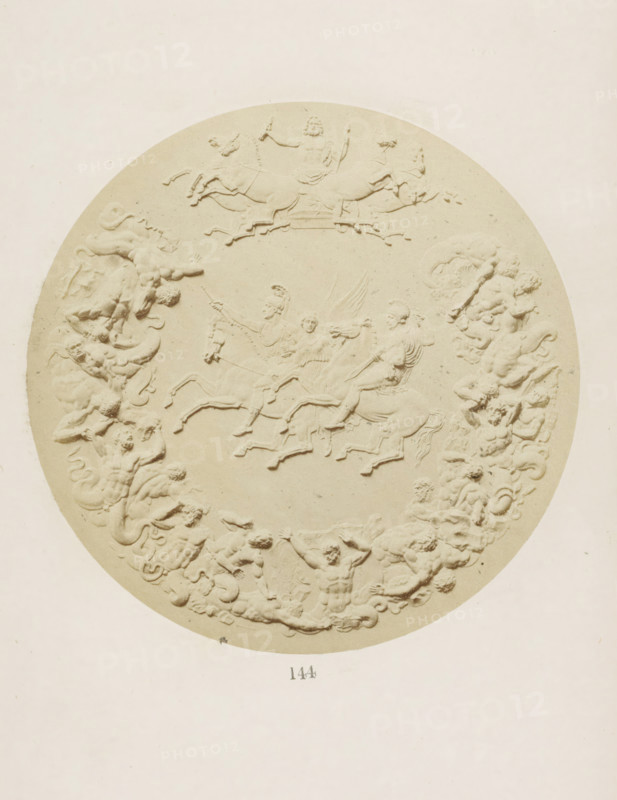 Commemorative medal in memory of the Battle of Waterloo with the Duke of Wellington and Gebhard von Blücher on horseback and surrounding the storming of Olympus by nineteen giants, photograph, page, number: '144', photographer: F. Cole, c. 1857 - in or before 1867, paper, albumen print, height 126 mm x width 126 mm, Photo after page 144., memorial medal, sculpture (relief, sculpture), A circular bas-relief in a pale, uniform color fills the image, showing raised sculpted figures of horses and human figures arranged in a wreath-like composition; at the top a chariot scene with a bearded figure holding implements and horses in motion; lower within the circle several riders on galloping horses and winged figures among them; the circular border is formed by intertwined reclining and seated figures with flowing hair and drapery, some holding objects, creating a continuous ornamental band against a plain background.