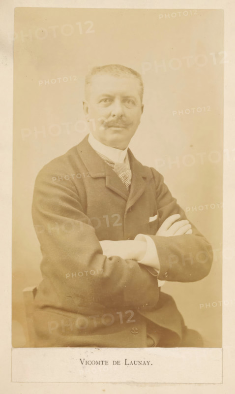 Vicomte De Launay, Portrait of Alphonse de Launay, photograph, page, c. 1881 - in or before 1891, photographer, paper, albumen print, height 153 mm x width 95 mm, Photo opposite title page., Person, Alphonse de Launay, portrait, self-portrait of artist, A sepia portrait of a man seated with arms crossed, wearing a dark suit jacket, a patterned necktie, and a white shirt with visible cuffs, showing a neatly trimmed moustache and short hair, set against a plain light background.