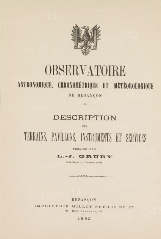 Astronomy observation, chronometry and météorologique de Besançon description of the terrains, pavillons, instruments and services, book, printer (person): Imprimerie Millot Frères et Cie, Besançon, publisher: Louis Jules Gruey, 1892, printer (person), pasteboard, biological material, paper, leather, albumen print, printing, lithography, printing and albumen printing, height 323 mm x width 240 mm x thickness 24 mm, The image shows a vertically oriented page with an ornate emblem of an eagle near the top and centered typographic elements arranged below it; the page background is a light beige with slight paper texture and small aged spots, and decorative flourishes separate sections of large centered headings and narrower lines of printed content, all in dark ink.