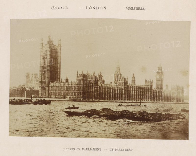 Houses of Parliament, photograph, page, London, c. 1876 - in or before 1886, photographer, paper, albumen print, height 143 mm x width 217 mm, river, Lower House, Parliament, Chamber, façade (of house or building), A wide sepia-toned photograph showing an ornate Gothic-style riverside palace with tall towers and a long facade extending along the water, small boats and barges floating on the river in the foreground, rippling water surfaces, distant low buildings partially visible behind the main structure, and a pale border surrounding the image.
