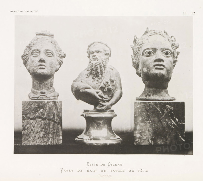 Bust of Silenus and two vases in the shape of a head, Buste de Silène Vases de bain en forme de tête, page, photomechanical print, number: 'Pl. 12', photographer: Stephane Geoffray, Paris, 1879, paper, collotype, photoprint, height 155 mm x width 200 mm, piece of sculpture, reproduction of a piece of sculpture, chest, bust - AA - female human figure, container of metal: bucket, can, canister, drum, tin, Three sculpted heads and an upper torso are shown mounted on pedestals. The left head has stylized hair pulled back with a flat element on top and a smooth neck rising from a marble pedestal. The central figure is a bearded torso with folded arms and a rounded base beneath it, the beard rendered in textured, curled strands. The right head has wide eyes, small horn-like projections on the hairline, and a similar marble pedestal beneath the neck. The background is light and plain, and the overall image is monochrome with varied stone and marble textures.