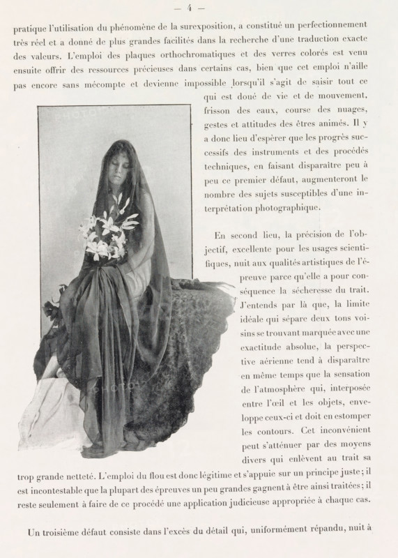 Veiled woman with flowers, page, photomechanical print, photographer: Constant Puyo, France, cliché maker: anonymous, c. 1886 - in or before 1896, paper, autotypie, height 153 mm x width 85 mm, adult woman, cut flowers, nosegay, bunch of flowers, veil, A grayscale photograph of a seated woman wearing a long flowing dress and a sheer veil, holding a bouquet of flowers in her lap, framed by a rectangular border and positioned on the left side of a page filled with printed text running around the image.