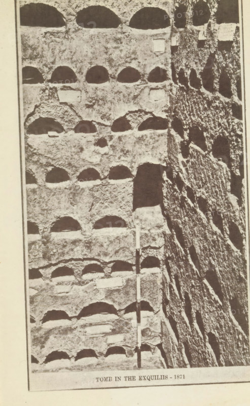 Columbaria Tomb in the Exquiliis, Wall with niches in a columbarium in Rome, page, photomechanical print, number: 'Plate IV.', 1871, paper, photoaquatint, height 223 mm x width 142 mm, urn, niche-tomb, wall-tomb, Rome, A vertical photograph of a stone wall with multiple rows of semi-circular recesses carved into its surface, showing rough textured rock and weathered edges, a taller narrow vertical rock face with irregular striations adjacent to the recessed wall, and a slender rod with alternating light and dark segments positioned upright against the wall.
