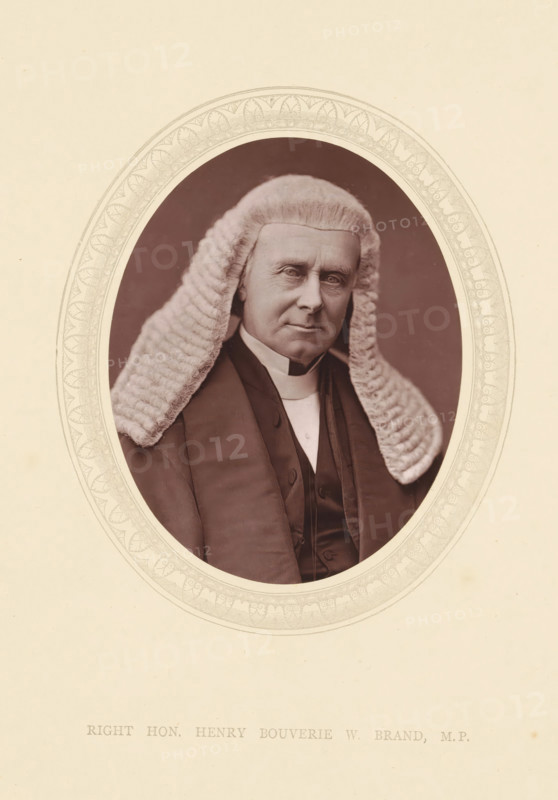Right hon. Henry Bouverie W. Brand MP, page, photomechanical print, photographer: Lock & Whitfield, cliché maker: anonymous, c. 1871 - in or before 1876, paper, Woodburytype, height 115 mm x width 89 mm, Person, Henry Brand, politician, eg party leader, historical persons (portraits and scenes from the life) ((full) bust portrait), An oval-framed sepia portrait of an older person wearing a full white curled wig and dark formal robes, the face showing a neutral expression and visible facial lines, the wig’s textured curls falling over the shoulders, the dark coat and vest visible beneath a high white collar, the ornate oval border surrounding the portrait set against a pale background.