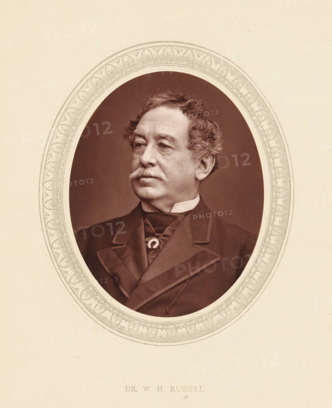 Dr. WH Russell, page, photomechanical print, photographer: Lock & Whitfield, cliché maker: anonymous, c. 1871 - in or before 1876, paper, Woodburytype, Woodbury Process, height 115 mm x width 89 mm, Person, William Howard Russell, journalist, reporter, historical persons (portraits and scenes from the life) ((full) bust portrait), A sepia portrait of an older man shown from the chest up inside an ornate oval frame with decorative leaf and scroll patterns, the man has wavy hair, bushy sideburns and a mustache, a high white collar is visible above a dark coat with wide lapels and a tied neckcloth, the background inside the oval is a plain dark tone and the outer area is a light cream paper.