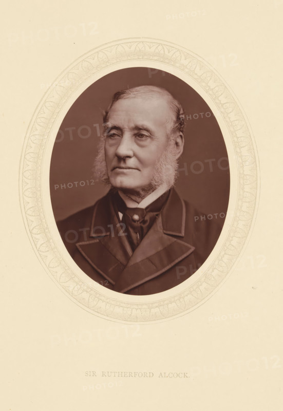 Sir Rutherford Alcock, page, photomechanical print, photographer: Lock & Whitfield, cliché maker: anonymous, c. 1871 - in or before 1876, paper, Woodburytype, Woodbury Process, height 115 mm x width 89 mm, Person, Rutherford Alcock, diplomacy, diplomat, historical persons (portraits and scenes from the life) ((full) bust portrait), A sepia-toned oval portrait of an older man with light sideburns and short hair, shown from the chest up and wearing a dark double-breasted coat with wide lapels and a high-collared shirt with a cravat, set against a plain dark background and surrounded by a decorative oval mat on a light cream page.