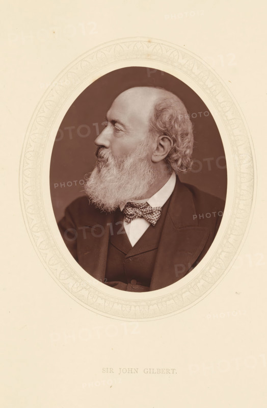 Sir John Gilbert, page, photomechanical print, photographer: Lock & Whitfield, cliché maker: anonymous, c. 1871 - in or before 1876, paper, Woodburytype, Woodbury Process, height 115 mm x width 89 mm, Person, John Gilbert, portrait, self-portrait of painter, historical persons (portraits and scenes from the life) ((full) bust portrait), A sepia-toned oval portrait of an older man shown in profile facing left, with a full white beard and mustache, receding hairline and curly hair at the back of his head, wearing a dark suit jacket and waistcoat over a white shirt and a patterned bow tie, set against a darker oval background and surrounded by a decorative pale border on a light sheet.