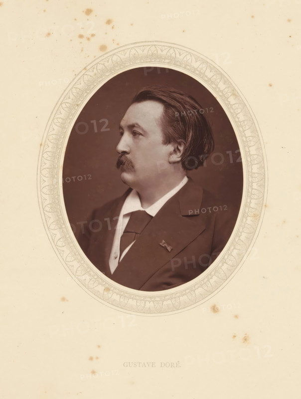 Gustave Doré, page, photomechanical print, photographer: Lock & Whitfield, cliché maker: anonymous, c. 1871 - in or before 1876, paper, Woodburytype, Woodbury Process, height 115 mm x width 89 mm, Person, graphic artist, historical persons (portraits and scenes from the life) ((full) bust portrait), An oval sepia portrait of a man in profile set within an ornate decorative oval frame on a cream paper background, showing the man's dark hair combed back, a thick mustache, a collared shirt with a tie and a dark jacket, with some scattered small brown spots and stains on the surrounding paper.