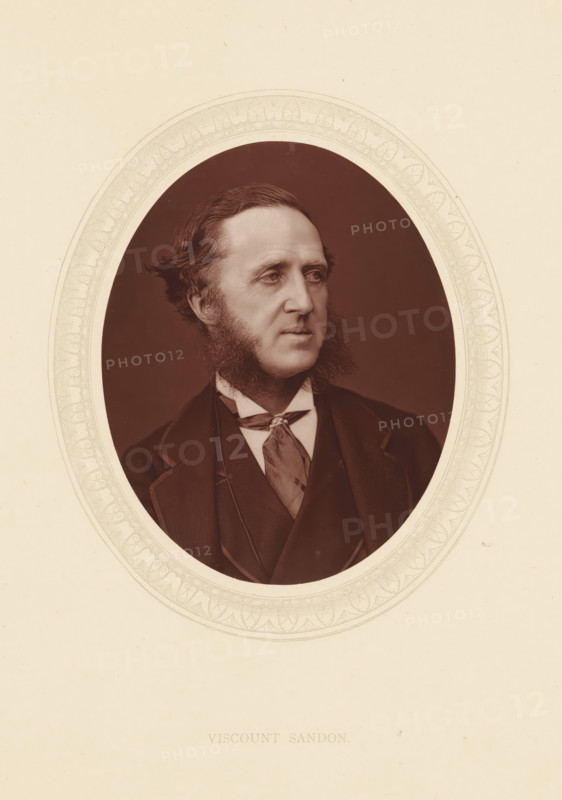 Viscount Sandon, page, photomechanical print, photographer: Lock & Whitfield, cliché maker: anonymous, c. 1873 - in or before 1878, paper, Woodburytype, Woodbury Process, height 115 mm x width 89 mm, Person, Dudley Ryder, politician, eg party leader, historical persons (portraits and scenes from the life) ((full) bust portrait), An oval-framed sepia portrait of a man shown from the chest up, facing slightly to his left, with wavy hair combed back and prominent sideburns extending along his jaw; he wears a dark jacket with wide lapels, a waistcoat, a high-collared shirt, and a patterned cravat tied at the neck, all set against a plain dark background and surrounded by a pale decorative oval border on a light background.