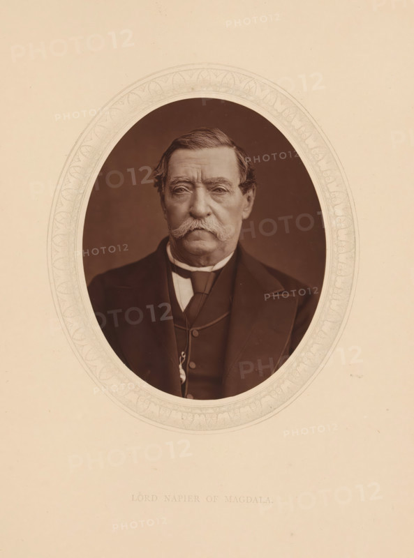 Lord Napier of Magdala, page, photomechanical print, photographer: Lock & Whitfield, cliché maker: anonymous, c. 1873 - in or before 1878, paper, Woodburytype, Woodbury Process, height 115 mm x width 89 mm, Person, Robert Napier, scholar, philosopher, historical persons (portraits and scenes from the life) ((full) bust portrait), An oval sepia portrait of an older man with a large, bushy mustache and neatly combed hair, wearing a dark suit jacket, waistcoat, and a high-collared shirt with a cravat, set against a plain darker background and surrounded by an ornate pale decorative border on a lighter sheet.
