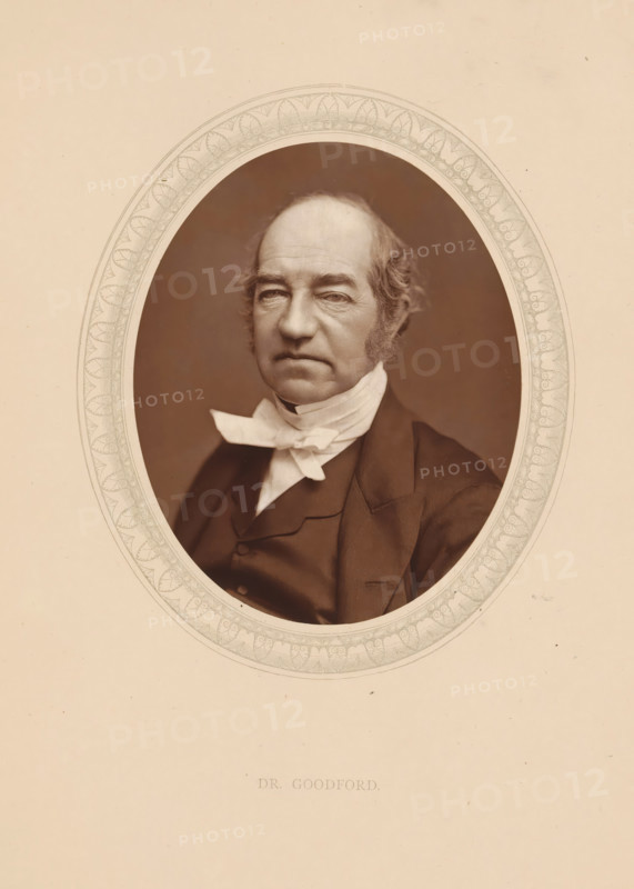 Dr. Goodford, page, photomechanical print, photographer: Lock & Whitfield, cliché maker: anonymous, c. 1873 - in or before 1878, paper, Woodburytype, Woodbury Process, height 115 mm x width 89 mm, Person, Charles Old Goodford, historical persons (portraits and scenes from the life) ((full) bust portrait), A sepia portrait of an older man shown from the chest up within an ornate oval frame, wearing a dark suit jacket and a white neckcloth tied in a bow, with short wavy hair and prominent sideburns, a furrowed forehead, and a neutral expression, set against a plain light background.