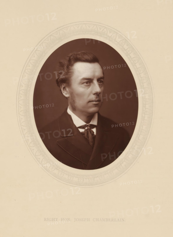 Right hon. Joseph Chamberlain, page, photomechanical print, photographer: Lock & Whitfield, cliché maker: anonymous, c. 1876 - in or before 1881, paper, Woodburytype, Woodbury Process, height 115 mm x width 89 mm, Person, Joseph Chamberlain, politician, eg party leader, historical persons (portraits and scenes from the life) ((full) bust portrait), A sepia-toned oval portrait of a man with neatly combed dark hair and sideburns, wearing a dark suit jacket, a white shirt collar, and a patterned necktie, set against a dark background and framed by a decorative light-colored oval mat on a pale page.