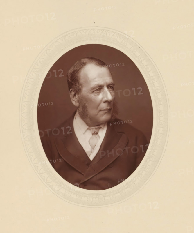 Serjeant Ballantine, page, photomechanical print, photographer: Lock & Whitfield, cliché maker: anonymous, c. 1877 - in or before 1882, paper, Woodburytype, Woodbury Process, height 115 mm x width 89 mm, Person, William Ballantine, lawyer, attorney at law, historical persons (portraits and scenes from the life) ((full) bust portrait), A sepia-toned oval portrait of an older man shown from the chest up, set against a pale background with a faint decorative oval border; he faces slightly to his right with a calm expression, short combed hair, prominent sideburns, and visible facial lines, wearing a dark jacket over a light shirt and a loosely tied cravat.