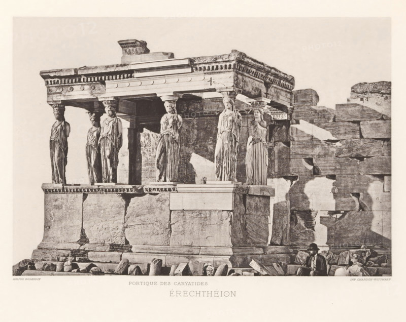 Érechthéion, Facade with caryatids of the Erechtheion on the Acropolis of Athens, page, photomechanical print, Athens, cliché maker: Dujardin, printer (person): Chardon-Wittmann, c. 1880 - in or before 1890, photographer, printer (person), Athene, Periféreia Protevoúsis, paper, photoaquatint, height 145 mm x width 215 mm, ruin of a building, architecture, caryatids, temple, shrine, Greek religion, Akropolis, Erechtheion, A sepia-toned photograph of an ancient stone structure showing a section of a building with a decorated horizontal entablature supported by sculpted female figures serving as columns; the figures wear draped garments and stand on a raised platform, each topped with a carved capital, and they are set against large weathered stone blocks forming the wall and base of the structure, with scattered stone fragments and rubble at the foreground; a man wearing a hat and coat sits among the stones near the lower right corner of the image.