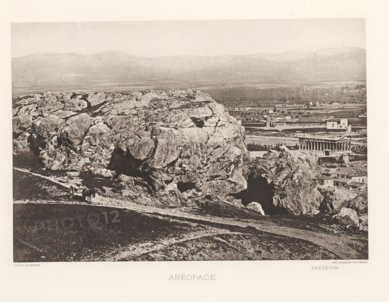 Aréopage, View of the Areopagus in Athens, page, photomechanical print, inscription: 'Théséion', Athens, cliché maker: Dujardin, printer (person): Chardon-Wittmann, c. 1880 - in or before 1890, photographer, printer (person), Athene, Periféreia Protevoúsis, paper, photoaquatint, height 145 mm x width 215 mm, landscape with ruins, (high) hill, court session (court of justice), Areopagus, A wide panoramic scene showing a rocky hillside in the foreground with large rough boulders and exposed rock faces, a dirt path running along the slope, and a simple cart with an animal standing beside it; beyond the rocks a flat plain stretches toward distant low hills, and near the middle right a classical temple with a rectangular colonnaded structure sits among scattered buildings and trees.