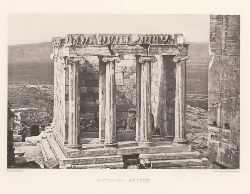 Temple of Athena Nikè on the Acropolis of Athens, Victoire aptère, page, photomechanical print, Athens, cliché maker: Dujardin, printer (person): Chardon-Wittmann, c. 1880 - in or before 1890, photographer, printer (person), Athene, Periféreia Protevoúsis, paper, photoaquatint, height 145 mm x width 215 mm, ruin of a building, architecture, temple, shrine, Greek religion, Acropolis, Temple of Athena Nikè, A stone structure with fluted columns and carved capitals stands on a stepped base, showing weathered blocks and worn surfaces; fragments of sculpted relief sit along the top edge, and broken stones and rubble lie around the base and interior; a partial statue or draped figure is visible among the ruins inside the columned space; a tall vertical stone wall is visible to the right, and a distant, hazy landscape stretches behind the ruins under a pale sky.