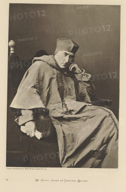 Mr. Henry Irving as Cardinal Wolsey, page, photomechanical print, photographer: Downey, William & Daniel, cliché maker: anonymous, c. 1883 - in or before 1893, paper, photoaquatint, height 216 mm x width 148 mm, Person, Henry Irving, portrait of actor, actress, A seated person wearing a long, flowing robe with visible buttons down the front and a square hat sits in a high-backed chair with a fringed armrest. The person rests one elbow on the chair arm and supports their head with a hand, looking slightly forward with a contemplative facial expression. The other hand holds a rolled object near the fringed armrest. The chair has a decorative finial at the top and dark upholstery. The background is plain and darker than the foreground, and the overall image is monochromatic with soft shadows and fabric folds visible across the robe.