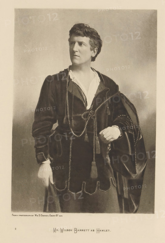 Mr. Wilson Barrett as Hamlet, page, photomechanical print, photographer: Downey, William & Daniel, cliché maker: anonymous, c. 1883 - in or before 1893, paper, photoaquatint, height 210 mm x width 147 mm, Person, Wilson Barrett, portrait of actor, actress, A sepia portrait of a person standing and facing slightly to the side, wearing a dark, ornate costume with a light-colored collar visible at the neckline and decorative braided cords with tassels draped across the torso, one hand resting near the waist and the other hanging down holding fabric, the costume featuring scalloped trim and beaded or studded edges, the subject has short wavy hair and a composed facial expression, and the background is a plain, softly shaded backdrop.