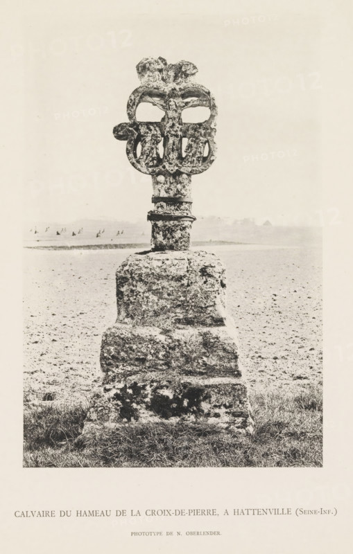 Calvaire du Hameau de la Croix-de-Pierre, A. Hattenville (Seine-Inf.), Stone calvary, page, photomechanical print, number: 'Pl. V.', photographer: N. Oberlender, cliché maker: Raoul Bonet (possibly), c. 1885 - in or before 1895, paper, collotype, phototype, height 206 mm x width 138 mm, sculpture, crucified Christ with other persons, A weathered stone monument stands on a grassy patch leading into a flat, open terrain, consisting of a rough rectangular base topped by a narrower shaft and an ornate carved head with symmetrical rounded openings; the stone surfaces display pitting and irregular texture, and the background shows a distant low horizon with faint shapes and a pale sky.