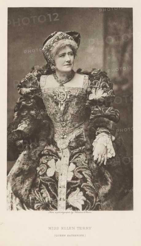 Miss Ellen Terry (Queen Katherine), page, photomechanical print, photographer: Window & Grove, cliché maker: anonymous, c. 1880 - in or before 1890, paper, photoaquatint, height 211 mm x width 131 mm, Person, Ellen Terry, portrait of actor, actress, A seated woman in an ornate historical costume fills the frame, wearing a richly decorated gown with a patterned fabric and heavy fur trim, puffed sleeves with embroidered floral motifs, and lace cuffs at her wrists; she has a jeweled brooch and layered necklaces at her square neckline and a decorated headpiece with textured fabric and embellishments atop short, waved hair, her expression neutral as she looks slightly to the side, one hand resting on her lap and the other on an armrest, and the background is plain and softly shaded.