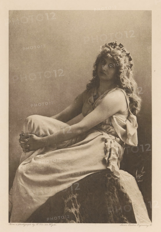 Miss Mary Anderson (Perdita), page, photomechanical print, photographer: Henry van der Weyde, cliché maker: Swan Electric Engraving Co., c. 1880 - in or before 1890, paper, photoaquatint, height 191 mm x width 127 mm, Person, Mary Anderson, portrait of actor, actress, A seated woman with long wavy hair wears a sleeveless draped gown and a wreath of leaves in her hair; she sits with her arms wrapped around her knees and gazes toward the viewer with a neutral expression, the image rendered in a soft monochrome with a plain background and draped fabric over the seat.