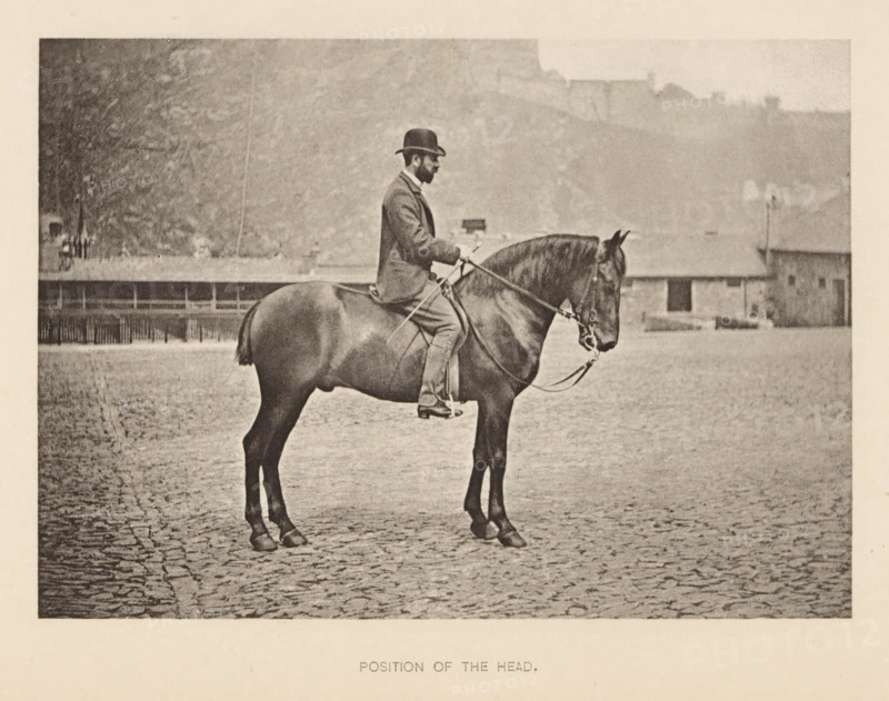 Position of the head, Man on a horse, page, photomechanical print, photographer: Alexander Nicol (possibly), Edinburgh (possibly), cliché maker: Römmler & Jonas, Dresden, c. 1879 - in or before 1889, paper, collotype, photoprint, height 98 mm x width 137 mm, horse, riding a horse, ass, or mule, rider, horseman, head-gear: bowler hat, A sepia-toned photograph showing a man seated on a horse in profile facing right, the man wearing a dark bowler hat and a suit with trousers and boots, holding the reins with both hands; the horse has a bridle and a short docked tail and stands on a cobbled surface, with a low building and a row of fencing visible in the background and a hazy hillside rising behind them.