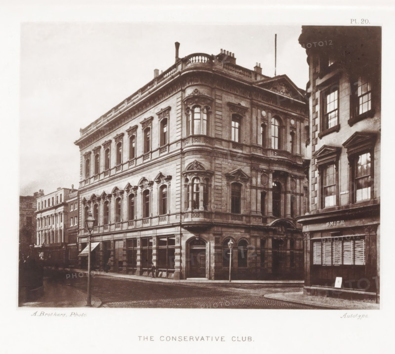 The Conservative Club, Façade of the Conservative Club in Manchester, page, photomechanical print, number: 'Pl. 20.', photographer: Brothers, Alfred, Manchester, cliché maker: anonymous, c. 1868 - in or before 1878, printer (person), paper, collotype, photoprint, height 145 mm x width 183 mm, façade (of house or building), A sepia-toned photograph of a street corner featuring a large ornate stone building with multiple stories, decorative window frames, balconies with balustrades, and sculpted architectural details around arched and rectangular windows; a rounded corner section with bay windows rises above the corner entrance, and a lamppost stands on the cobbled road in front; adjacent buildings with tall windows and pedimented window surrounds are visible to the right and along the street, and a shopfront with a shuttered window appears at street level.