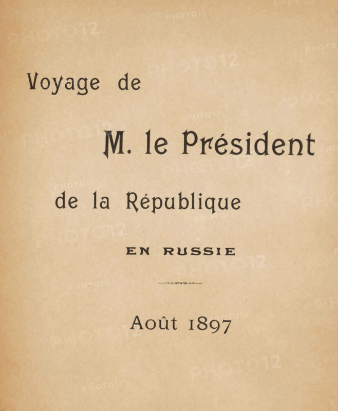 Voyage de M. le Président de la République en Russie, Août 1897, book, writer (clerical worker): Paul Belon, photographer: Paul Gers, 1897, writer (clerical worker), textile materials, paper, linen (material), printing, collotype, height 277 mm x width 200 mm x thickness 11 mm, A tan, slightly mottled paper background with dark serif characters arranged in several horizontal lines across the upper and middle areas, including a larger central line of bold, stylized letters and smaller lines above and below, and a small decorative flourish in the center; the lower portion of the page is mostly empty with the paper texture visible.