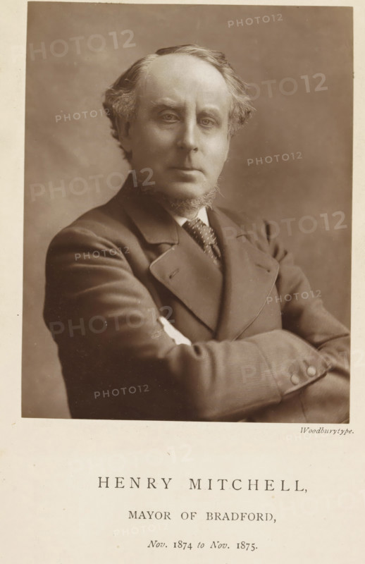 Portrait of Henry Mitchell, Henry Mitchell, mayor of Bradford, page, photomechanical print, inscription: 'Nov. 1874 to Nov. 1875.', photographer: Appleton & Co., Bradford (England), cliché maker: anonymous, c. 1871 - in or before 1881, paper, Woodburytype, height 116 mm x width 91 mm, Person, historical persons (portraits and scenes from the life) ((full) bust portrait), A sepia portrait of a middle-aged man shown from the waist up with arms crossed, wearing a suit jacket, waistcoat, and patterned tie, with sideburns and a trimmed beard, light-colored hair combed back, a neutral facial expression, and a plain softly shaded background.