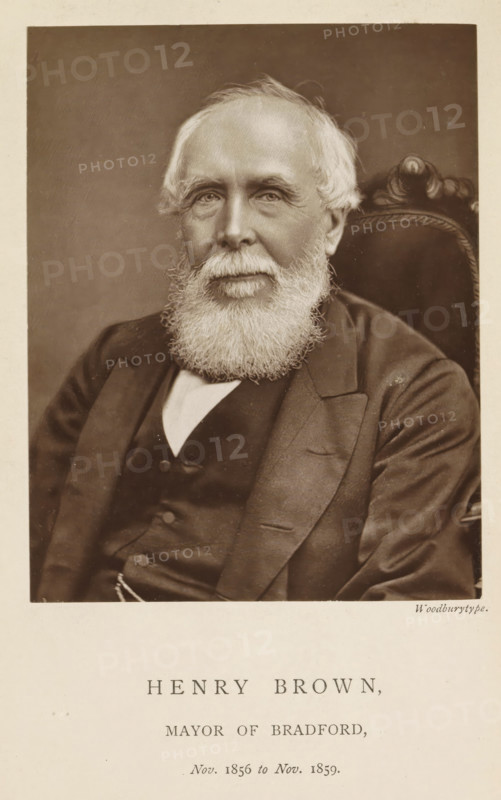 Henry Brown, mayor of Bradford, Portrait of Henry Brown, page, photomechanical print, inscription: 'Nov. 1856 to Nov. 1859.', photographer: Appleton & Co., Bradford (England), cliché maker: anonymous, c. 1871 - in or before 1881, paper, Woodburytype, Woodburytypepie, height 116 mm x width 91 mm, historical persons (portraits and scenes from the life) ((full) bust portrait), A sepia portrait of an older man seated in an upholstered chair, shown from the chest up, with a full white beard and short white hair, wearing a dark suit jacket over a dark waistcoat and a light shirt visible at the collar, his expression calm and eyes looking forward, the background plain and darker than the surrounding light border.