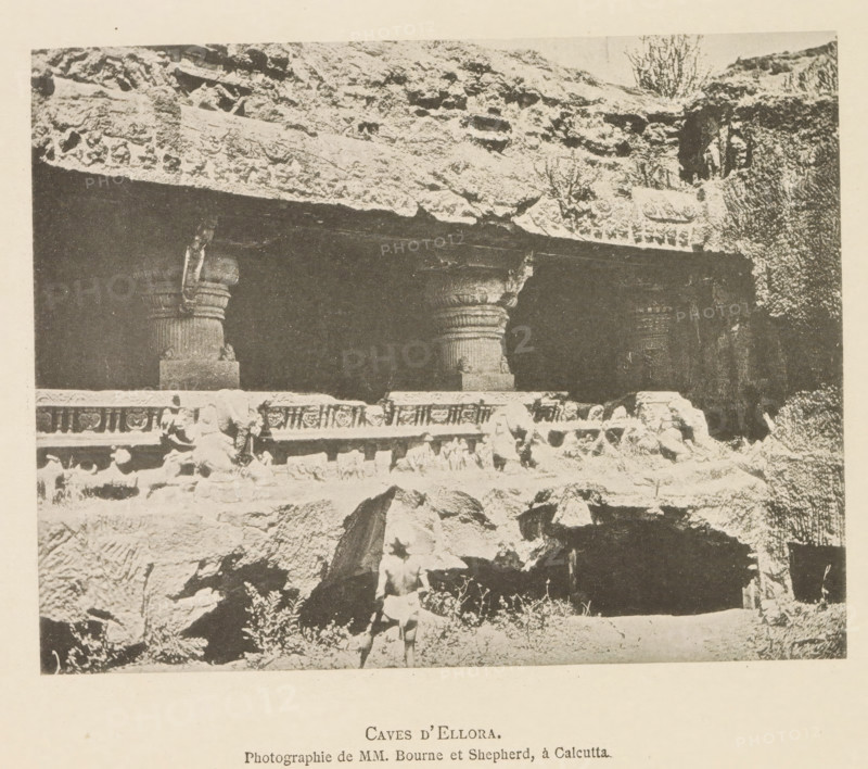 Caves d'Ellora, Exterior of an ornamented cave temple at Ellora, page, photomechanical print, inscription: 'Photographie de MM. Bourne et Shepherd, à Calcutta.', photographer: Bourne & Shepherd, Ellora, cliché maker: anonymous, c. 1875 - in or before 1884, Bourne & Shepherd, photographer, cliché maker, paper, collotype, photoprint, height 118 mm x width 153 mm, cave, grotto, temple, shrine, non-Christian religions, sculpture (relief, sculpture), A monochrome photograph showing a rock-cut facade with a dark recessed opening supported by carved columns and a carved horizontal band above, a rocky overhang with textured stone and small vegetation above the opening, rough stone foreground and scattered rocks, and a person standing near the front wearing minimal clothing.