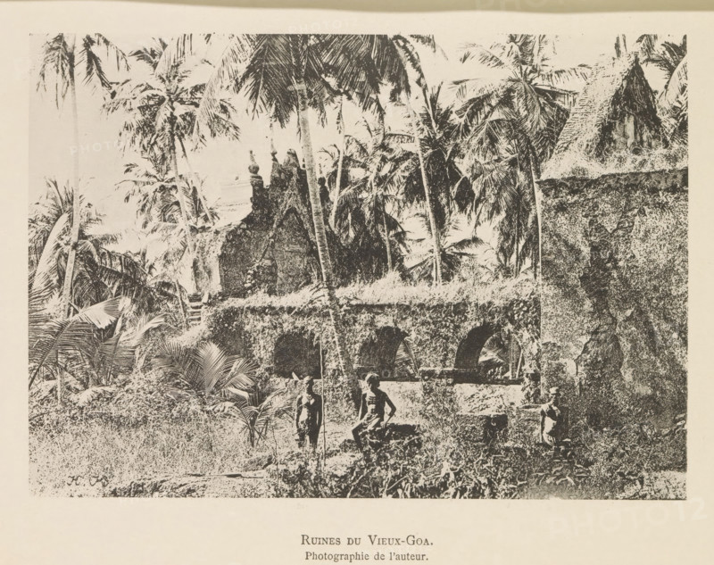 Ruin of a building in Oud-Goa, Ruines du Vieux-Goa, page, photomechanical print, inscription: 'Photographie de l'autoriteit.', inscription: 'HK', photographer: Hugues Krafft, Oud-Goa, cliché maker: anonymous, in or after 1882 - in or before 1883, Hugues Krafft, photographer, cliché maker, Goa, paper, collotype, photoprint, height 122 mm x width 172 mm, ruin of a building, architecture, trees: palm-tree, A monochrome image shows a landscape filled with tall palm trees and dense tropical foliage, with textured stone ruins including arched openings and a thatched roof structure partially visible; three bare-chested figures stand and sit among the grass and vegetation near the ruined stonework, and the scene is bordered by a light margin.